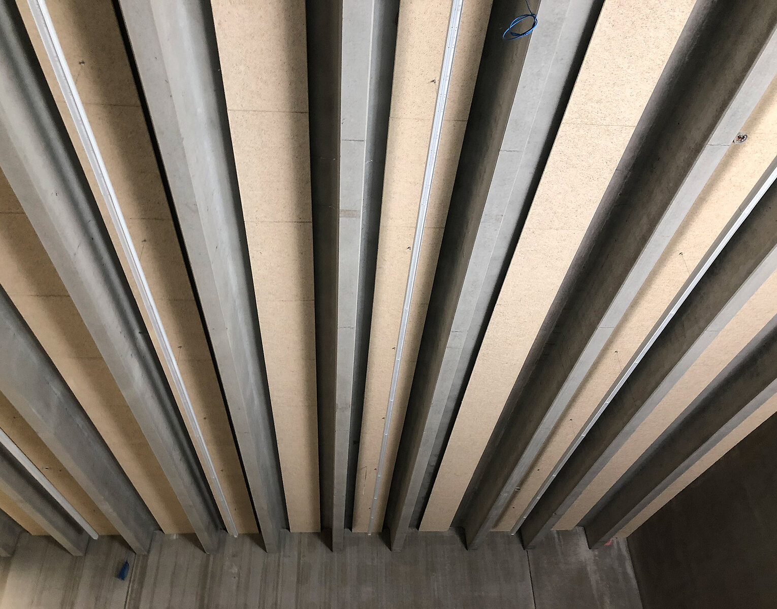 Deckenbalken aus Beton oder Stahl, die in gleichmäßigen Abständen parallel verlaufen, vermutlich Teil einer Gebäudedecke oder Brückenkonstruktion.