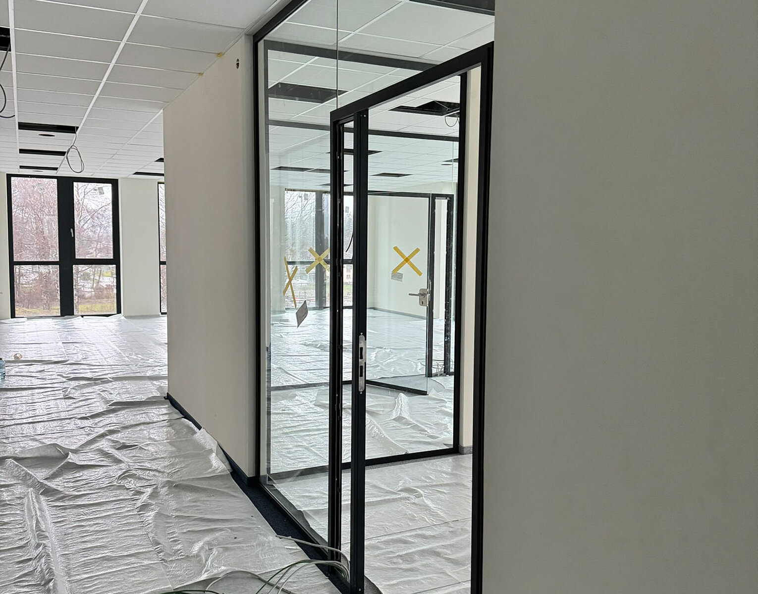 Innenraum eines modernen Gebäudes in Bau oder Renovierung mit Glaswänden und Bodenabdeckung aus Folie zum Schutz.
